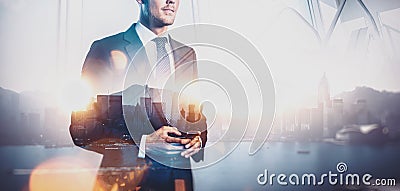 Photo of businessman holding smartphone. Double exposure, city on the background. Wide Stock Photo