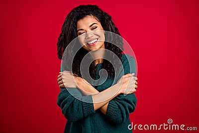 Photo of calm joyful young dark skin woman smile hug herself good mood love isolated on red color background Stock Photo