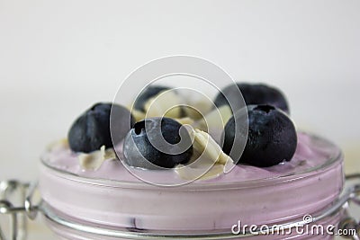 In this photo we can see a handmade blueberry yogurt decorated with blueberries and almonds in a close plane Stock Photo