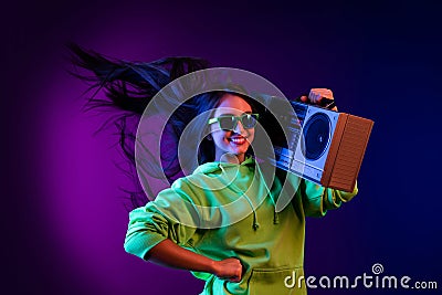 Photo of charming cheerful young woman hold shoulder boombox fly hair smile isolated on dark gradient background Stock Photo