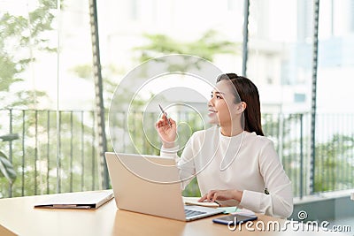 Photo of charming chinese businesswoman sitting at table and working with documents and laptop isolated Stock Photo