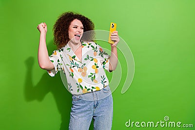 Photo of charming lucky girl dressed print shirt rising fist winning game modern gadget empty space isolated green color Stock Photo