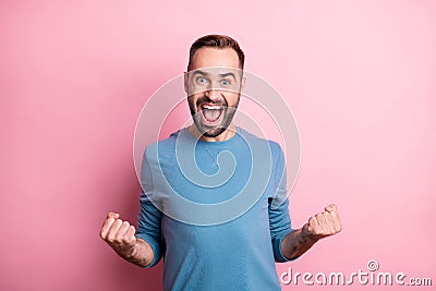 Photo of charming lucky young guy wear blue pullover rising fists open mouth isolated pink color background Stock Photo