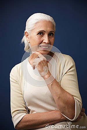 Photo of charming mature woman in beige tshirt, holding her chin Stock Photo