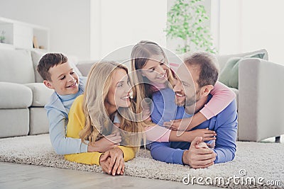 Photo of charming mom dad lying carpet hold piggyback two adorable little kids girl boy in house indoors Stock Photo