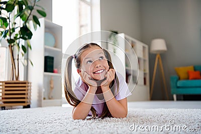 Photo of cheerful creative minded girl lying carpet floor look away fantasize imagine apartment indoors Stock Photo