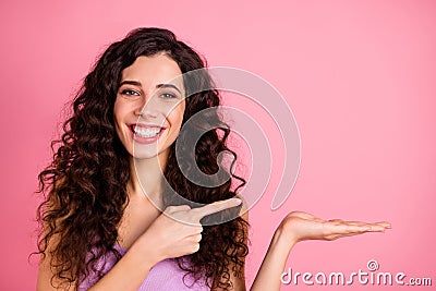 Photo of cheerful cute charming pretty girlfriend pointing at object in on her palm while isolated with pink background Stock Photo