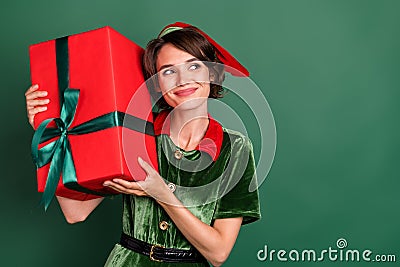 Photo of cheerful dreamy lady hold box look empty space wear elf costume hat isolated green color background Stock Photo