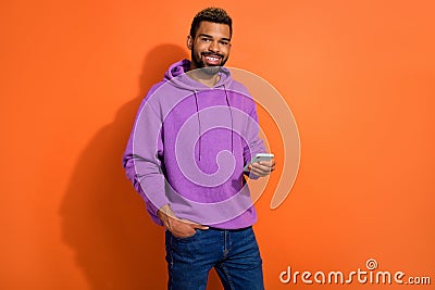 Photo of cheerful guy boy dressed sylish outfit chatting modern device isolated on orange color background Stock Photo