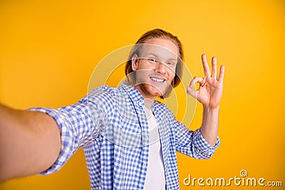 Photo of cheerful positive funky handsome checkered guy showing you ok sign taking selfie approving actions wearing blue Stock Photo