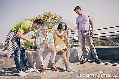 Photo of cheerful pretty girl guys sit in company eat watch telephone have fun party on roof terrace outside Stock Photo