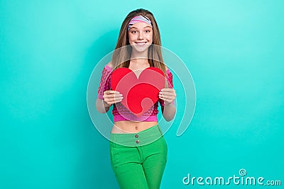 Photo of cheerful sweet schoolgirl wear pink crop top holding red paper card isolated turquoise color background Stock Photo