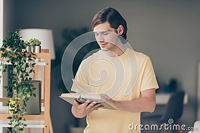 Photo of cheerful young creative guy read book education time think wear yellow t-shirt home indoors Stock Photo