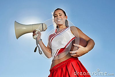 Cheerleader Holding Football and Megaphone Stock Photo