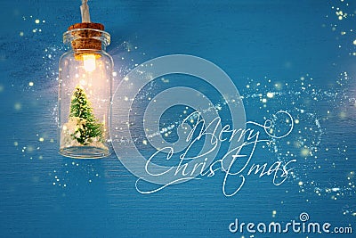 photo of Christmas tree in the masson jar garland light over wooden blue background. Stock Photo