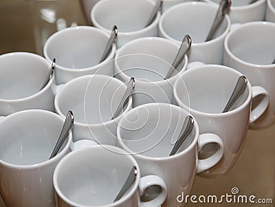 Photo closely standing diagonal rows together 13 white porcelain mugs with stainless steel spoons Stock Photo
