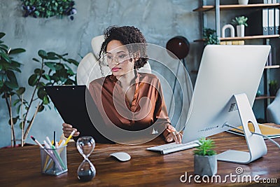 Photo of concentrated secretary sitting chair hold clipboard keyboard typing workplace business center indoors Stock Photo