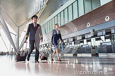 Portrait of confident pilot with stewardess walking in airport Stock Photo