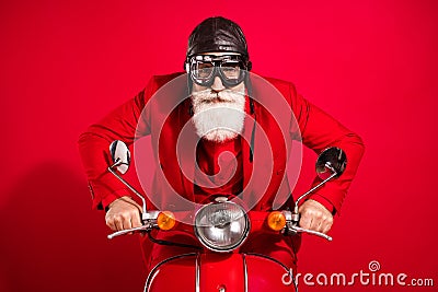 Photo of cool careful driver santa claus ride bike serious face wear goggles leather helmet suit on red color background Stock Photo