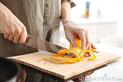 Photo cropped of caucasian woman cooking dinner with vegetables, cutting ripe fresh sweet peppers in kitchen Stock Photo