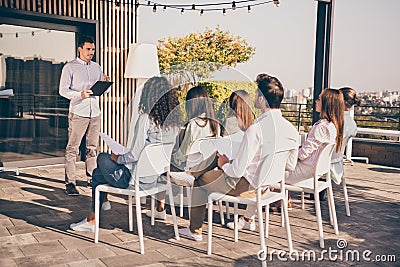 Photo of crowd of sitting people listen to recruitment manager hold clipboard tell about tasks outdoors Stock Photo
