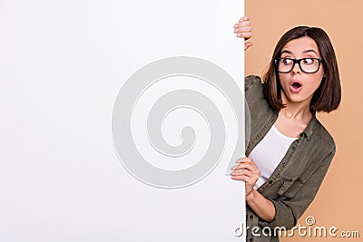 Photo of curious shocked lady look poster information wear specs khaki shirt beige color background Stock Photo