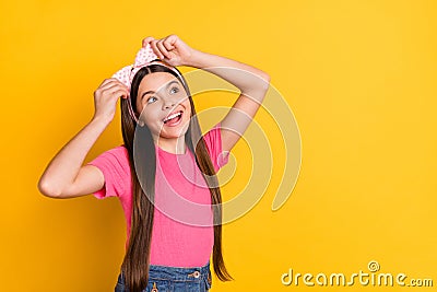 Photo of cute charming school girl wear pink t-shirt arms band looking empty space smiling isolated yellow color Stock Photo