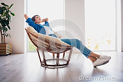 Photo of cute lovely satisfied girl sitting soft chair holding hands behind head enjoying free time in flat Stock Photo