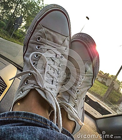 Photo depicting tennis shoes resting on a car dashboard. Stock Photo