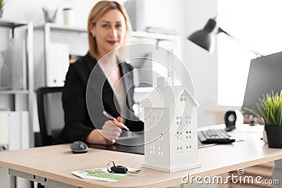 Photo with depth of field, a dedicated focus on the layout of the house. Young girl working in the office. Stock Photo