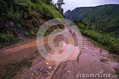 Dirt road in spring mountains with lots of muddy puddles after the rain - Sainj Valley, Kullu, Himachal, India Stock Photo