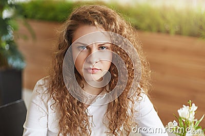 Photo of dissatisfied curly female model frowns face, feels tired and annoyed as waits for someone for long time in cafe, doesn`t Stock Photo