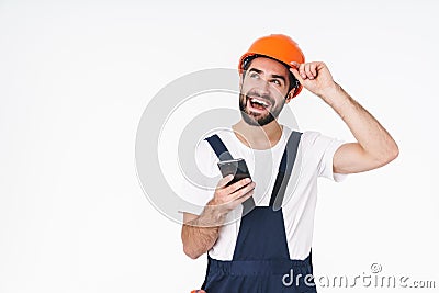 Positive young man builder in helmet using mobile phone Stock Photo