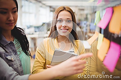 Photo editor standing near female coworkers pointing on sticky note Stock Photo