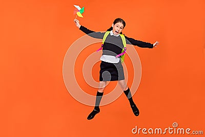 Photo of energetic schoolgirl jump hold propeller toy wear uniform rucksack isolated orange color background Stock Photo