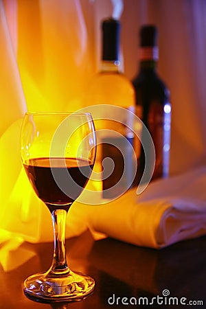 Photo-filled red wine glass transparent glass on the background of two full bottles of red and white wine. Stock Photo
