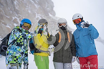 Photo of four happy snowboarders in helmet on background of mountains. Stock Photo
