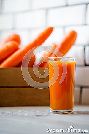 Photo of fresh carrots in a wooden box and a glass of freshly squeezed juice Stock Photo