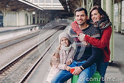 Photo of friendly family have good relationship, have trip during vacation, pose at platform of railway station. Lovely woman Stock Photo