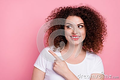 Photo of friendly woman with perming coiffure dressed white t-shirt look directing at promo empty space isolated on pink Stock Photo