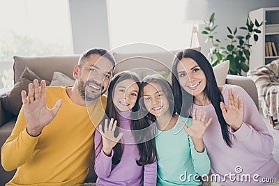 Photo of full family four people two small children waving hand look camera wear colorful pullover in living room Stock Photo