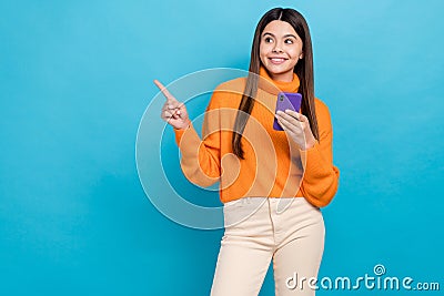 Photo of funny friendly interested girl wear knit turtleneck directing look empty space hold phone isolated on blue Stock Photo