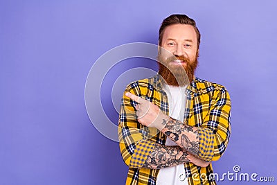 Photo of funny redhead foxy bearded tattoo guy wear plaid shirt direct finger empty space banner isolated purple color Stock Photo