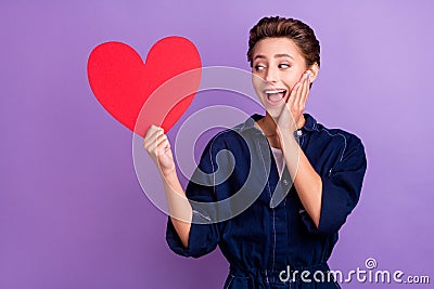 Photo of funny young lady hold look heart wear jeans overall isolated on violet color background Stock Photo