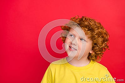 Photo of ginger dreamy inspired boy look up empty space wear yellow t-shirt isolated red color background Stock Photo