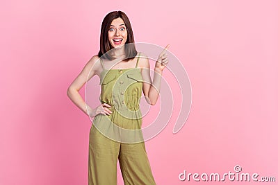 Photo of girlish adorable gorgeous woman wear khaki overall impressed pointing empty space hand on waist isolated on Stock Photo