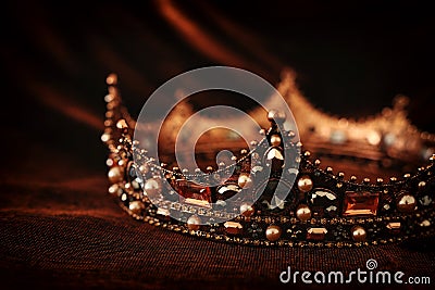 photo of gold crown over gothic dark silk background. Medieval period concept. Stock Photo