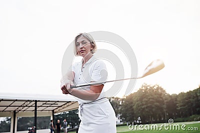 Photo of gorgeous blonde adult woman holding golf stick at the green sport field Stock Photo