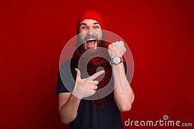 Photo of happy bearded guy, pointing at his newa watch, and dela Stock Photo