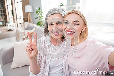 Photo of happy positive nice woman and old lady parent make selfie v-sign smile indoors inside house home Stock Photo